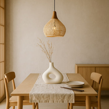 Dining room with wooden table, chairs, and a vase with dried plants under a woven pendant lighting​.