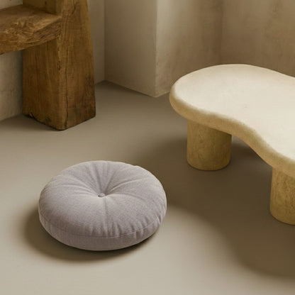Round gray seat cushions on a beige floor with a stone-like stool in the background.