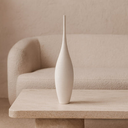 Tall decorative vase​ on a beige table with a neutral background
