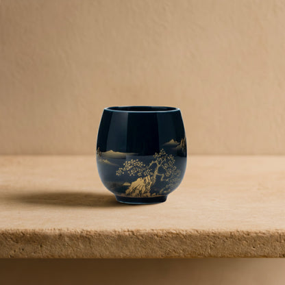 Blue tea cup handmade​ with gold floral design on a wooden surface with a warm light background