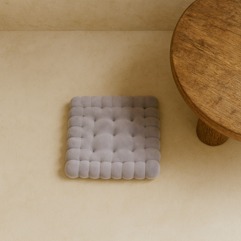 Gray thick floor cushion on a beige floor with a wooden table in the corner