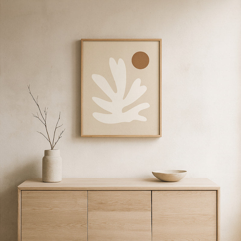 Wabi sabi art print​ on a wall above a wooden cabinet with decorative items.