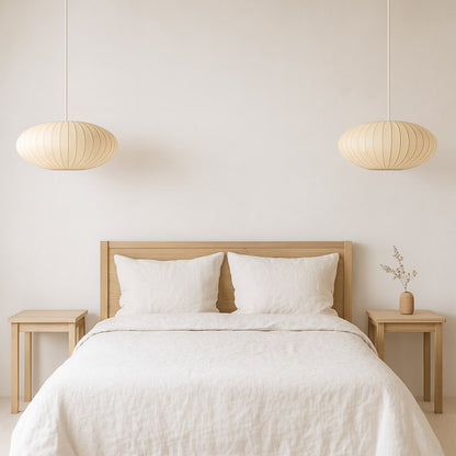 Bedroom with wooden bed frame, white bedding, and wabi sabi bamboo fixture light​