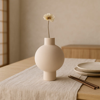 Beige wabi sabi plant pots with a single white flower on a wooden table with a neutral background