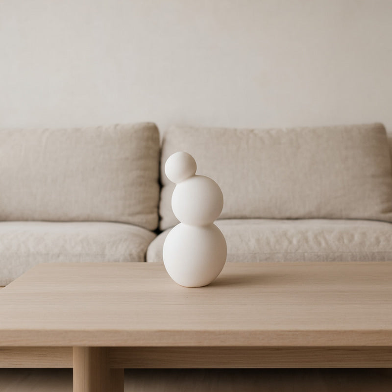 White wabi sabi pot on a wooden coffee table with a beige sofa in the background
