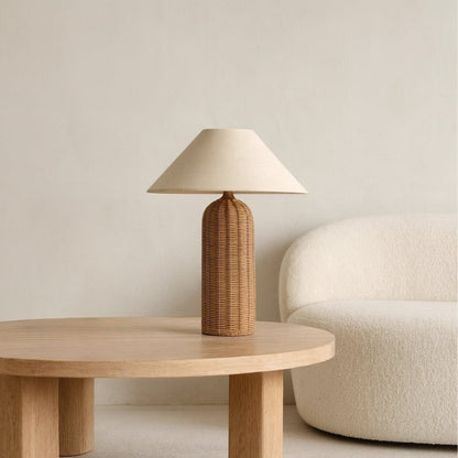 Wabi sabi table lamp with wicker base and beige lampshade on a white background