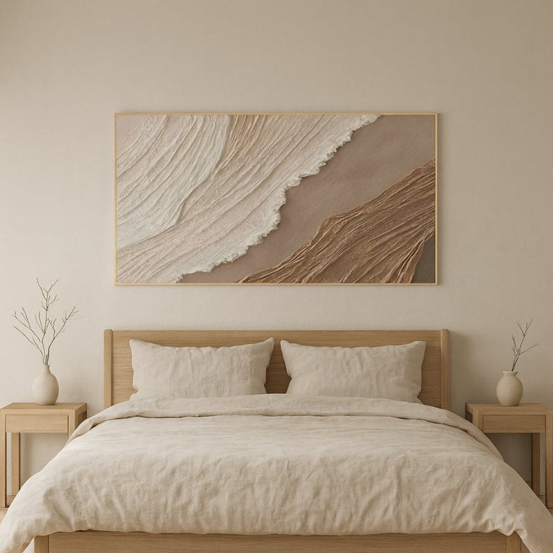 Neatly made bed with wooden headboard and  wabi sabi textured wall art.