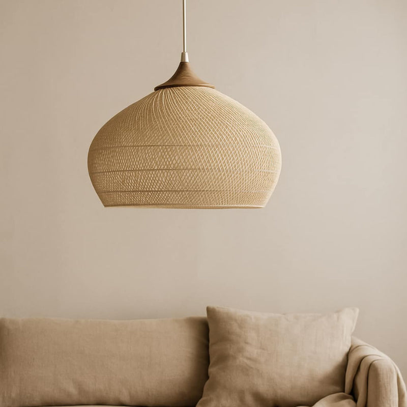 Wabi sabi wicker pendant light​ ceiling above a beige sofa against a neutral wall.