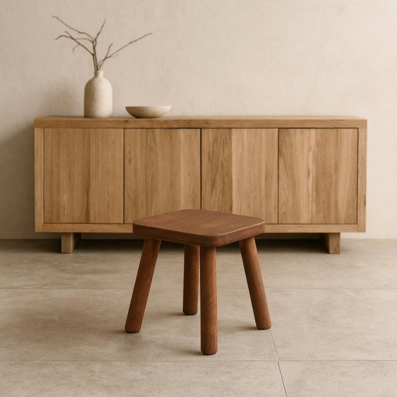 Wooden sideboard with a vase and bowl on top, accompanied by a wabi sabi wooden stool.