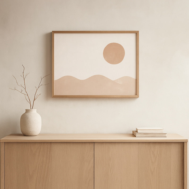 Framed wall abstract decor of a sun and mountains on a wall above a wooden cabinet.