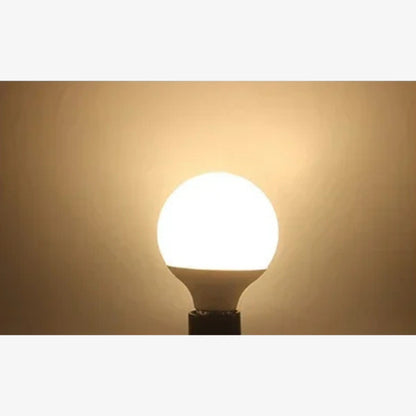 Light bulb emitting a warm light glow against a beige background