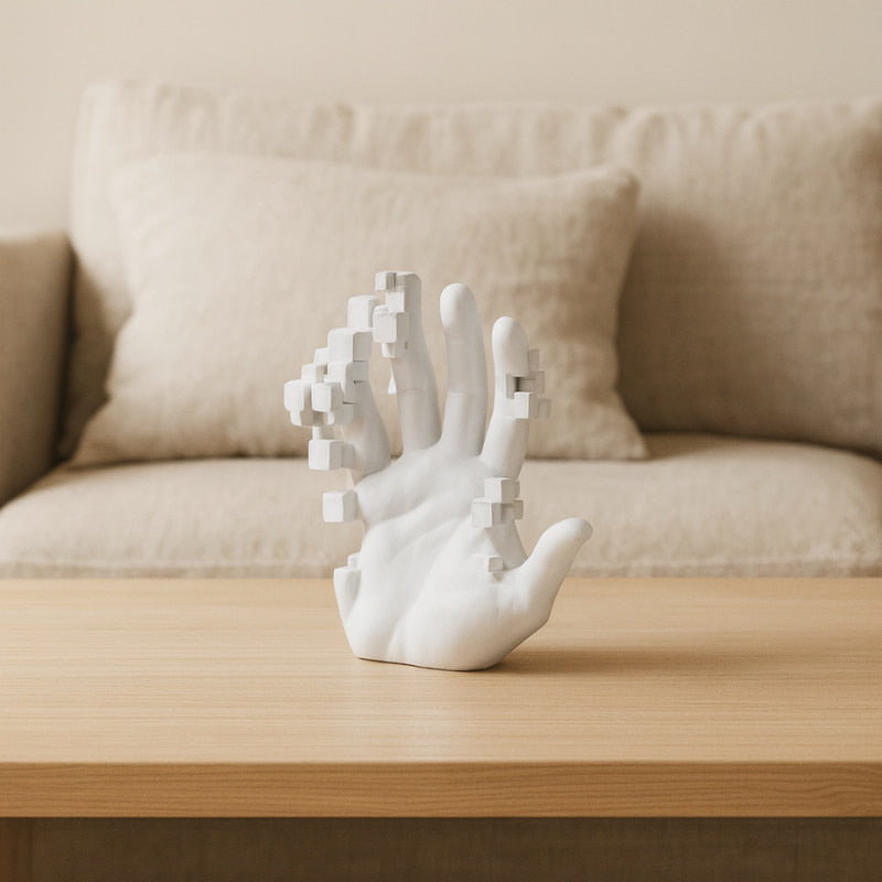White hand sculpture on a wooden table with a beige sofa in the background
