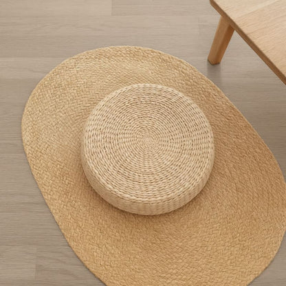 woven meditation cushion​ on a wooden floor with a small woven stool in the center.